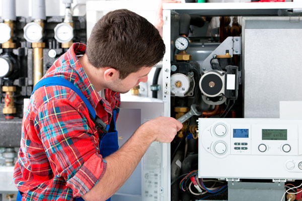 HVAC technician inspecting and repairing boiler controls in Eloy