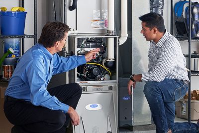 HVAC technician explaining furnace repair and maintenance to a homeowner in Eloy, AZ